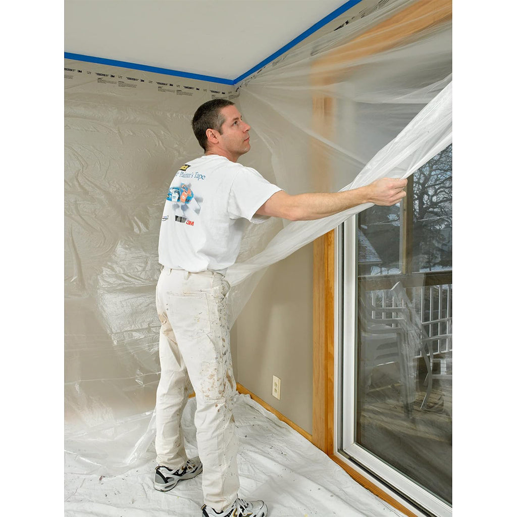 Contractor applying 3M CP9 plastic to protect large window and wall from paint