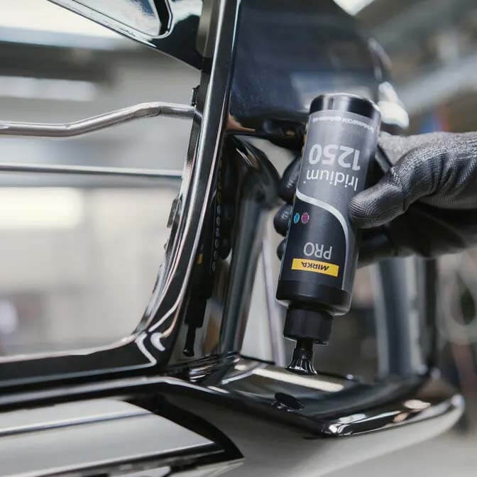 Close-up of Mirka PRO Iridium 1250 water-based polish being used on a black car panel