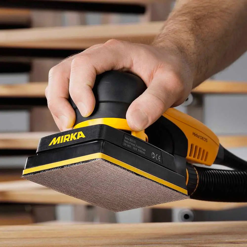 Tradie using a Mirka DEOS sander with an Abranet Ace net abrasive on a wooden surface