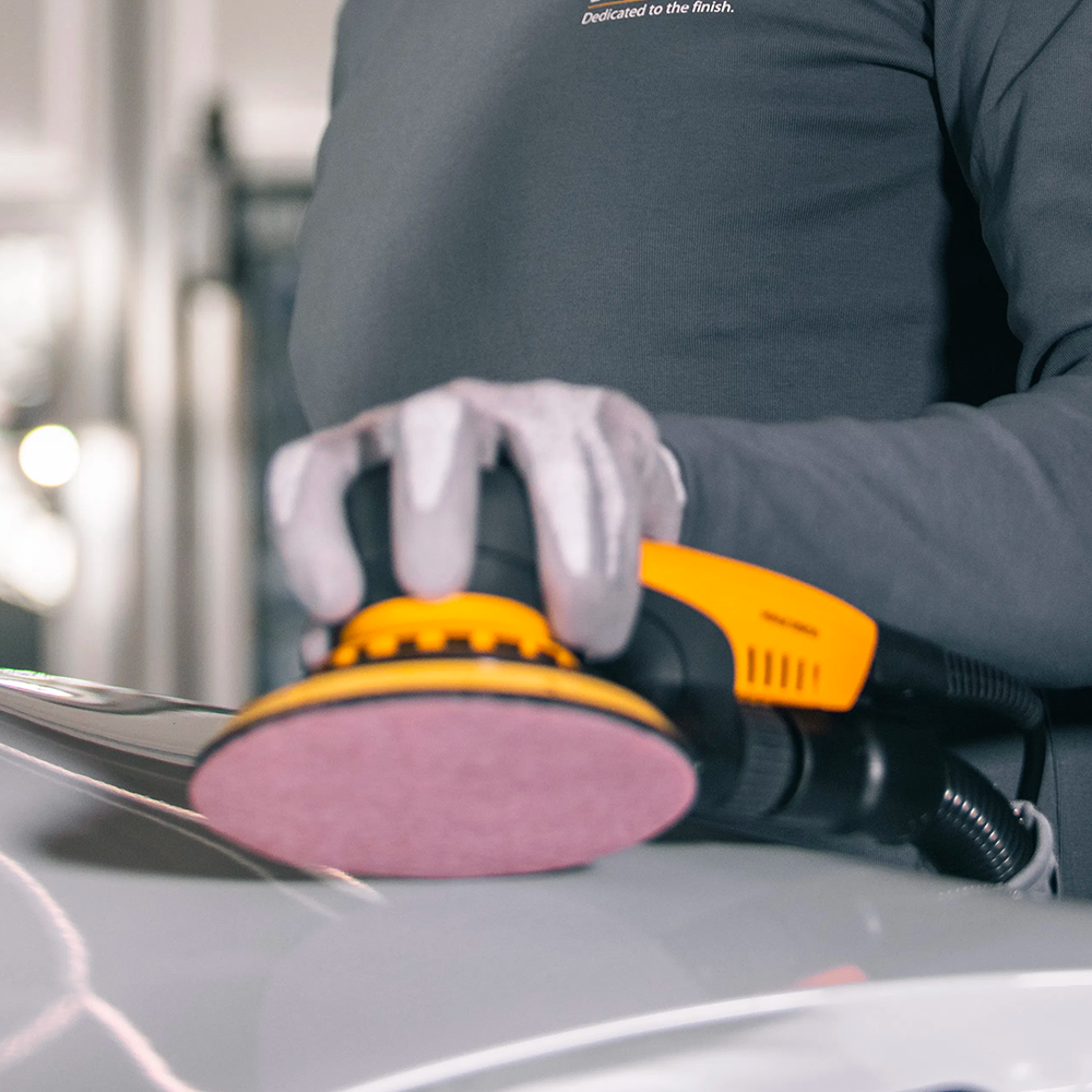 Professional using a Mirka sander with an Abranet Ace HD disc for automotive paint stripping