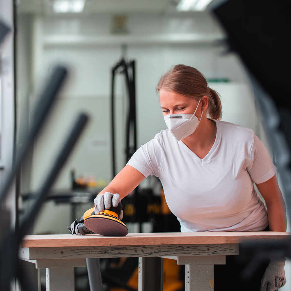 Tradie wearing a respirator while sanding a large timber surface with Abranet Ace HD