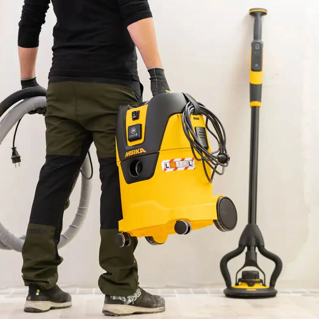 Tradie carrying the lightweight 8kg Mirka dust extractor using the integrated handle