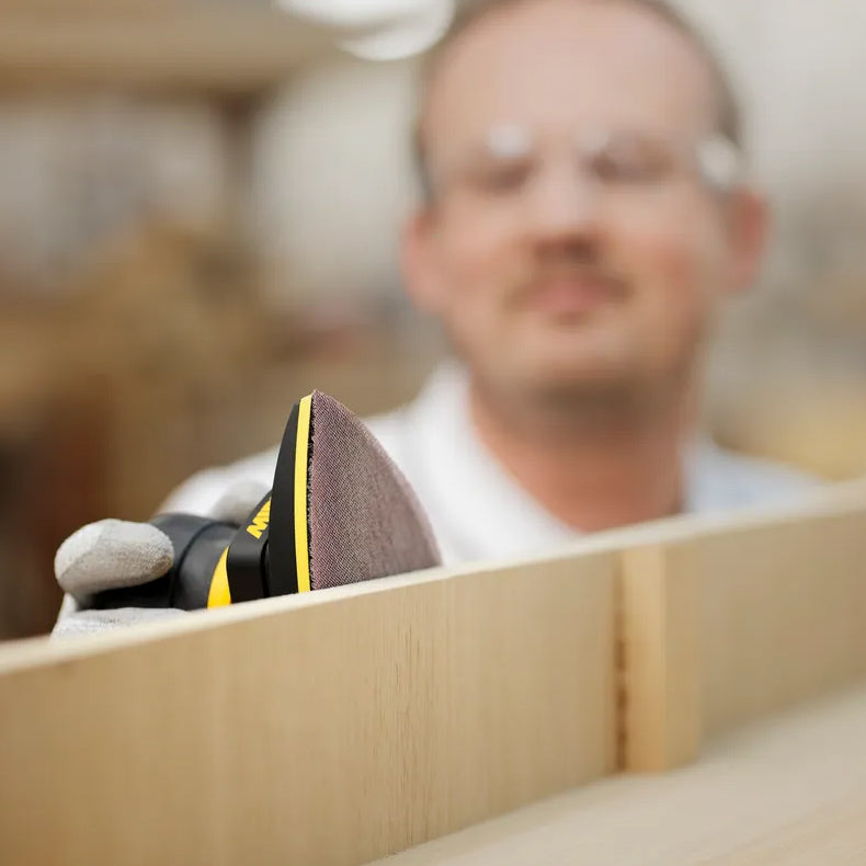 Professional woodworker using Mirka DEOS II Delta for fine finishing of timber furniture