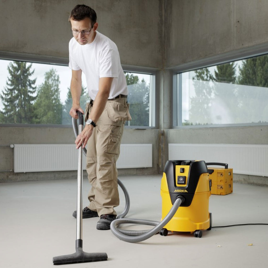 Tradie cleaning workshop floor with Mirka dust extractor and floor nozzle attachment