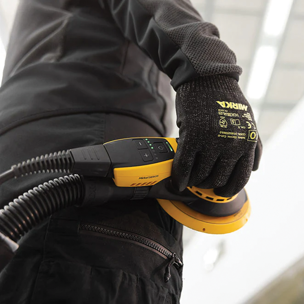 Tradie holding Mirka DEROS II with a professional dust extraction hose sleeve attached