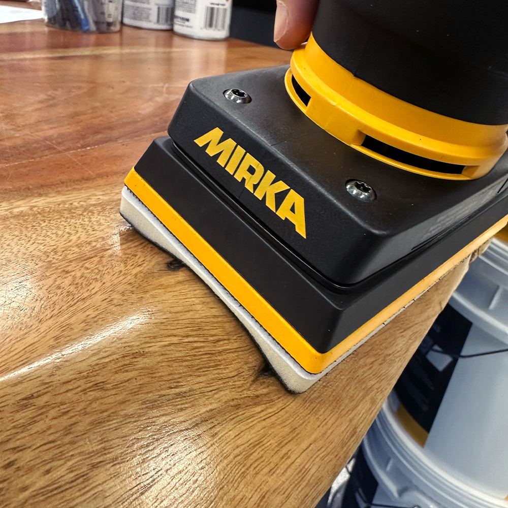 Sanding a curved timber surface with a flexible Mirka DEOS interface pad for a smooth finish