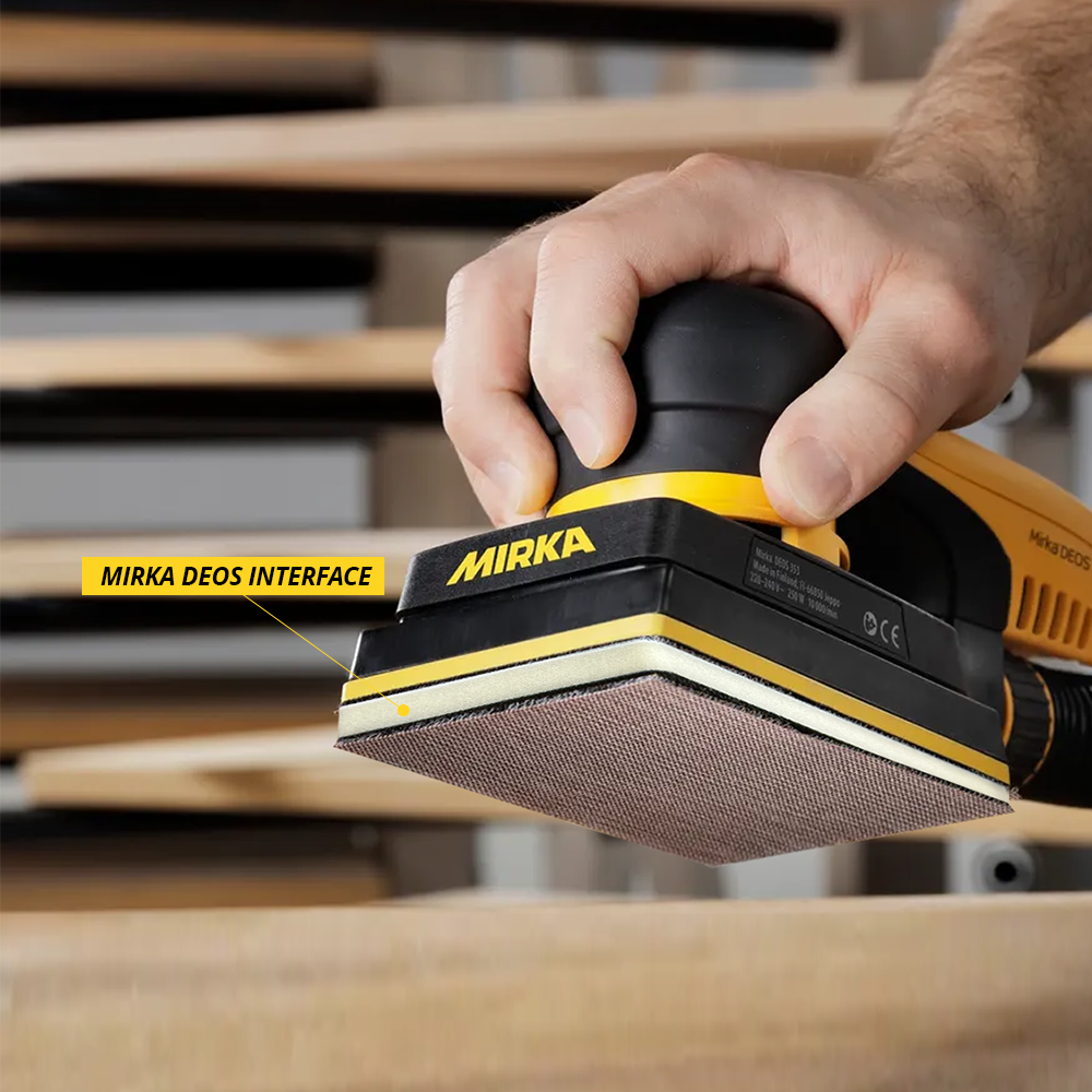 Close-up of the Mirka DEOS interface pad showing its flexibility on a wooden workpiece