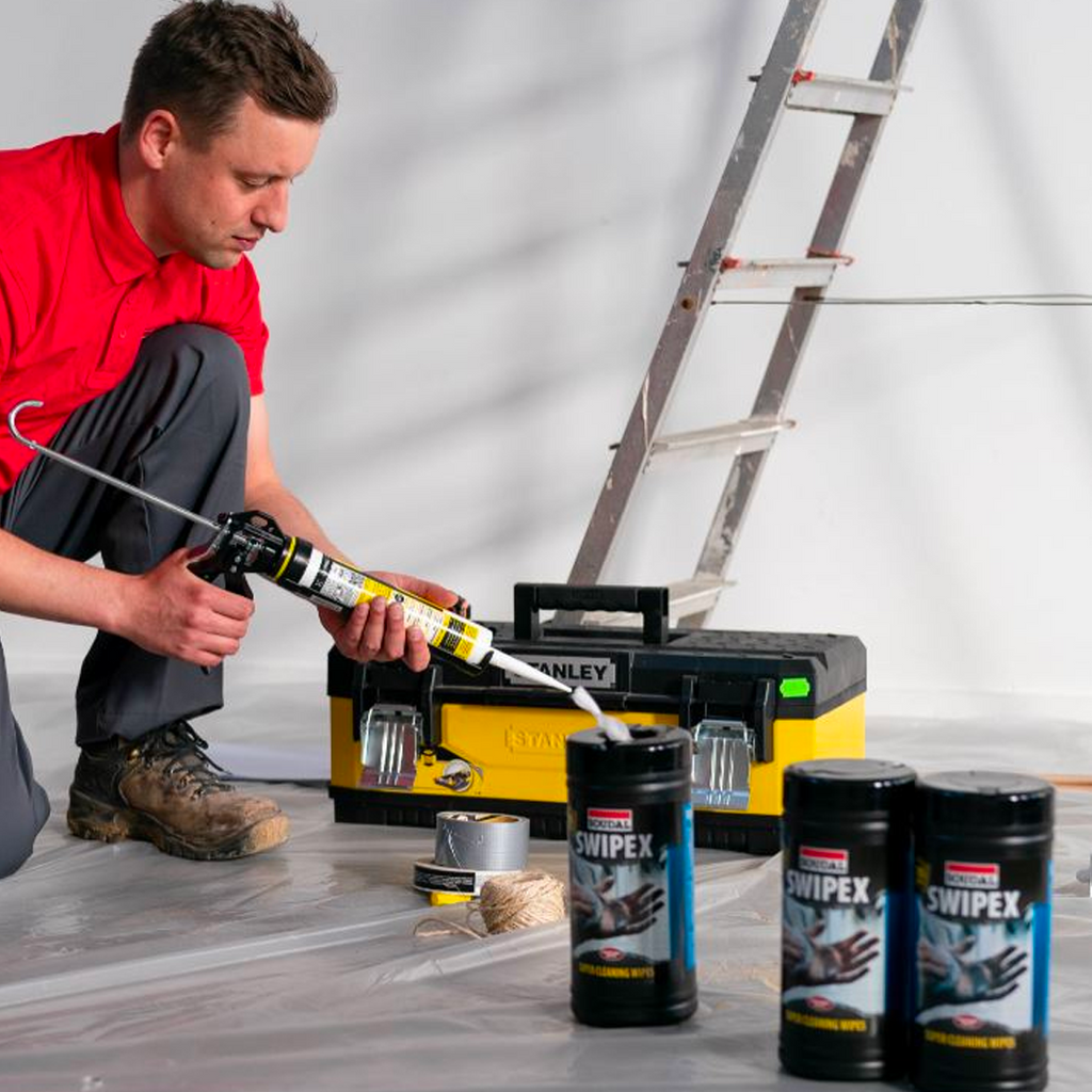 Australian tradesman with a tub of Soudal Swipex wipes and a caulking gun on a job site